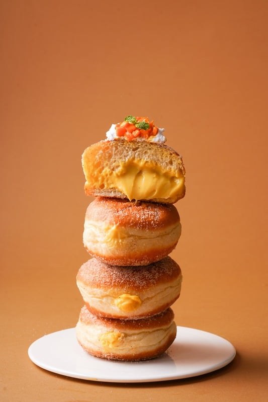 Stack of golden pastries topped with cream on a white plate